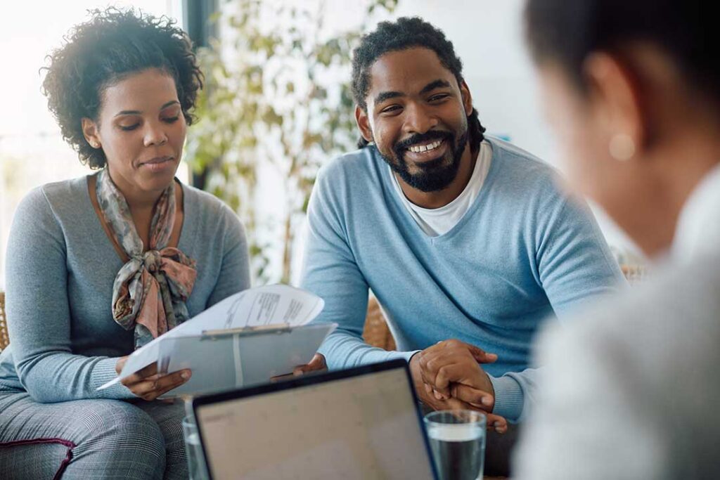 Family reviewing life insurance documents at a kitchen table beside a calculator and folder.