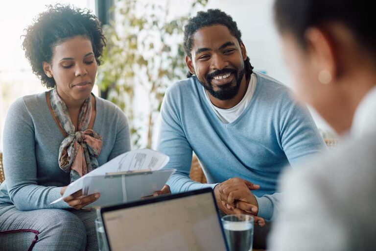 Family reviewing life insurance documents at a kitchen table beside a calculator and folder.